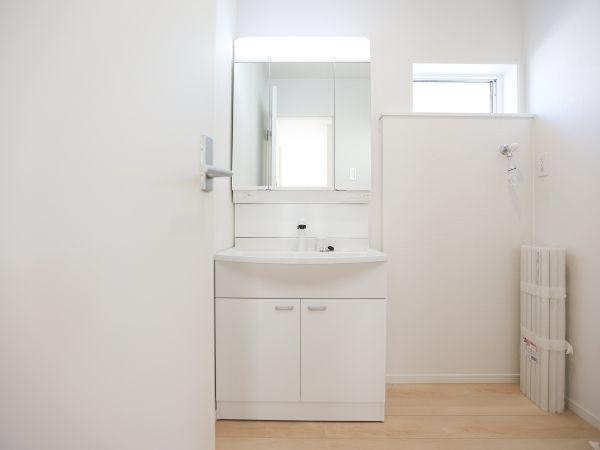 泉町第1-1号棟の独立洗面台|三面鏡タイプの洗面化粧台は、角度を変えて身だしなみをチェックできる実用性の高い仕様。収納スペースも広く、スキンケア用品や小物類もすっきり整理できます。毎日の準備が快適になる設備です♪