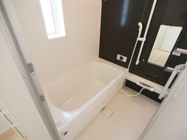 泉町第1-1号棟の浴室|明るい窓付きで自然光が入るバスルームです。手すりが設置されており安心してご利用いただけます。シンプルで清潔感のある内装です。