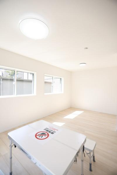 泉町第1-1号棟の居間・リビング|3つの窓から自然光がたっぷりと差し込むリビングです。白を基調とした内装が空間をより明るく感じさせます。広々としたフローリングでさまざまなレイアウトに対応できます。現代的な照明が天井に設置されています。