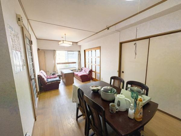 サンコーポ新川の居間・リビング|広々としたリビングは奥まで光が届く設計となっています。大きな窓からは明るい日差しが入ります。ダイニングテーブルを置いても余裕のある空間です。和室との仕切りには引き戸が採用されています。