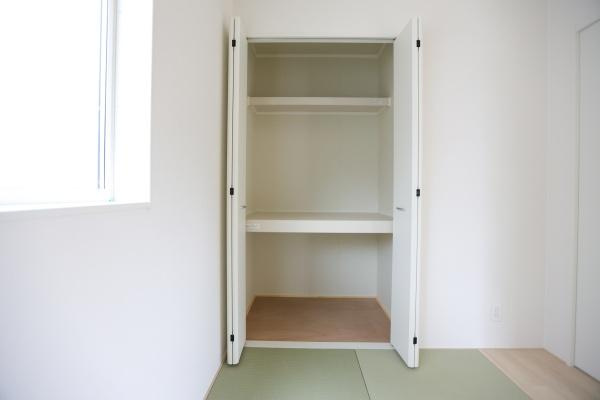 寒田北町第1-2号棟の収納|開き戸タイプの収納スペースが設置されています。棚付きで使いやすい設計です。清潔感のあるカラーで室内と調和しています。窓からの採光も収納周囲を明るくしています。