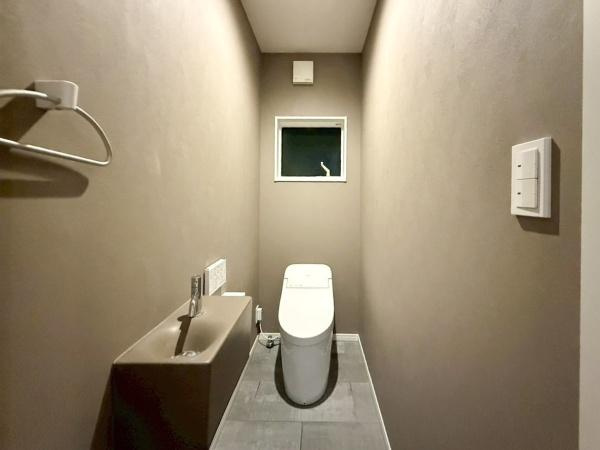 駄原中古のトイレ|落ち着いた色合いの壁が印象的なトイレです。小窓から自然光が入り空間に明るさを加えています。手洗いカウンターが設置されており使い勝手にも配慮されています。