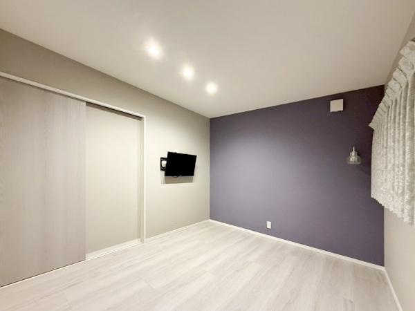 駄原中古の洋室|やさしい色合いのフローリングとアクセントクロスが調和した洋室です。テレビは壁付けで設置可能なため、すっきりとした印象になります。ダウンライトが明るさをしっかり確保。