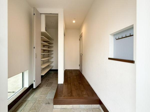 駄原中古の玄関|玄関は明るい空間が広がり、収納も充実しています。ウォークスルータイプのシューズクロークで扉もしっかりあり、急な来客時にも安心！シンプルな壁面にはフックも備え付けられています。