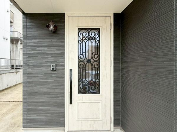 駄原中古の玄関|玄関扉の黒いアイアン調デザインがアクセントになっています。淡い色合いの玄関ドアが重厚感を演出しています。壁の素材感が引き立ちモダンな雰囲気を感じられます。