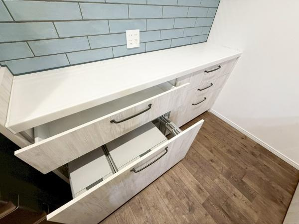 駄原中古のキッチン|引き出しタイプの収納が設けられており整理しやすい空間。壁面にはコンセントがあり家電の使用にも便利です。清潔感のある白を基調としたデザインが印象的。木目調の床との調和が取れたキッチンです。