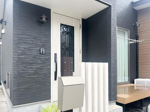 駄原中古の玄関|玄関ドアにはデザイン性のあるガラスパネルが採用されています。モダンな外観に調和した色合いが印象的です。ポストや外灯などの設備もスッキリ配置されています。軒下には雨除けがあり機能性にも配慮されています。