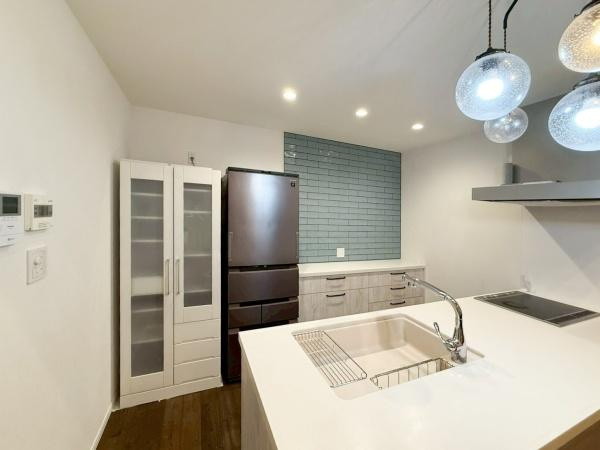 駄原中古のキッチン|収納スペースがしっかりと確保されたキッチンです。広々としたカウンターが使いやすそうです。天井照明が空間を明るく照らし、壁面のタイルがアクセントになっています。清潔感のある雰囲気です。