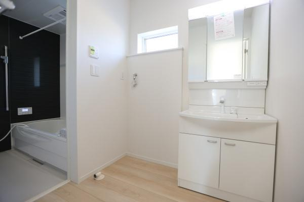 猪野第4-1号棟の独立洗面台|洗面所は白を基調とした清潔感のある空間です。大きな鏡付きの洗面台が設置されています。収納スペースも充実しています。浴室と隣接しており使い勝手の良いレイアウトです。窓もあり明るさを感じられます。
