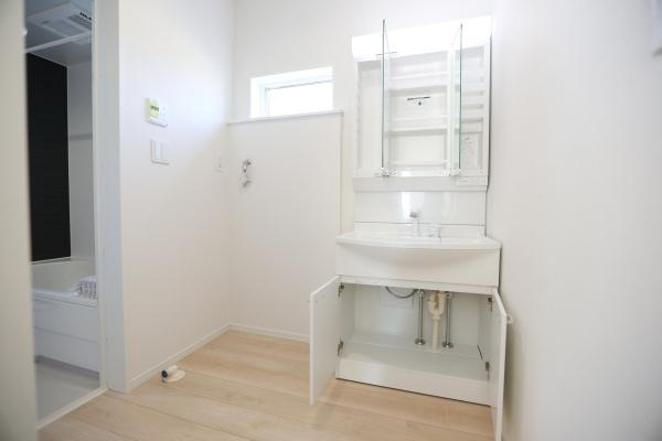 猪野第4-1号棟の独立洗面台|清潔感のある空間が広がる洗面所です。収納スペースも充実しており使い勝手に配慮されています。窓からの採光により明るい雰囲気です。洗面台下の扉付き収納もポイントです。