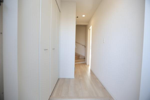 猪野第4-1号棟の玄関|玄関はホワイトを基調とした明るい印象です。収納スペースも備わっておりすっきりとした空間が広がります。廊下から階段への動線もスムーズです。シンプルな仕上がりで使いやすさが感じられます。