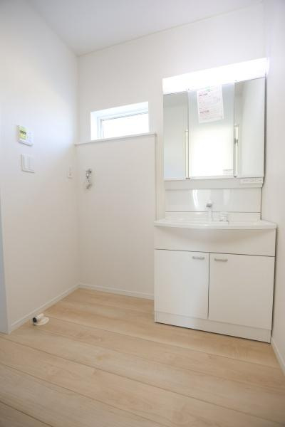 猪野第4-1号棟の独立洗面台|明るい色合いのフローリングと白を基調とした洗面台で清潔感のある空間です。大きな鏡が視界を広げてくれます。窓もあり換気がしやすい設計です。収納スペースがあるため整理がしやすい洗面所です。