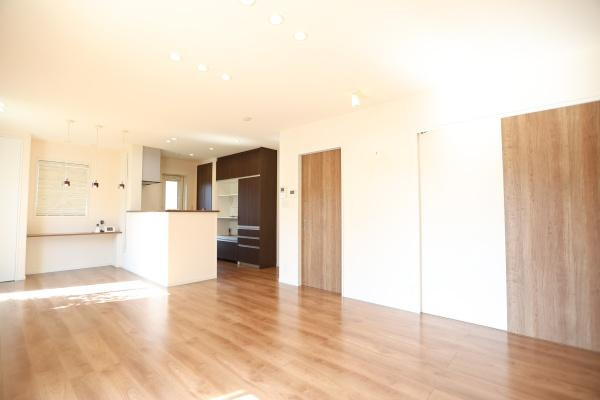 大字角子原　中古の居間・リビング|広々としたリビングは明るい陽射しが差し込む開放感のある空間です。床の質感と木目調の建具が落ち着いた雰囲気を演出しています。白を基調とした内装がより空間を広く感じさせます。