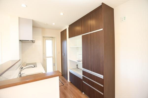 大字角子原　中古の居間・リビング|木目調の収納が印象的なリビングです。明るい色合いの壁と床が空間を広く感じさせます。対面式のキッチンがあり使い勝手の良い間取りとなっています。