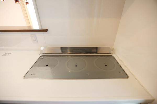 大字角子原　中古のキッチン|フラットなIHクッキングヒーターが設置されておりお手入れがしやすいです。すっきりとしたデザインでキッチン全体が広々と感じられます。作業スペースも確保されていますので調理も快適に行えます。