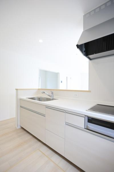 寒田北町第1-1号棟のキッチン|ホワイトを基調としたキッチンは空間がすっきりとした印象です。収納が豊富で整理整頓がしやすい造りになっています。作業スペースも広くさまざまな用途に対応できます。キッチンフードやコンロも設置されています。