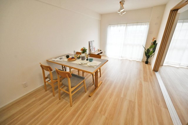 吹田ロイヤルマンションの居間・リビング|白を基調とした開放感あふれるLDKは約12.8帖の広さを確保。間口いっぱいの大きな窓から陽ざしが入り、窓から外への視界も広がるため、明るく開放感があるリビング・ダイニングになります。