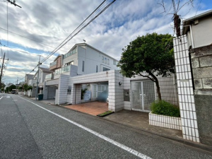 【前面道路含む現地写真】 | シンボルツリーの緑が彩りを添える清潔感あふれるエントランス。周囲は低層の建物が並ぶ閑静な住宅街で穏やかな時間が流れます。プライバシーに配慮された設計が日々の暮らしに心地よい安心感を与えてくれます。