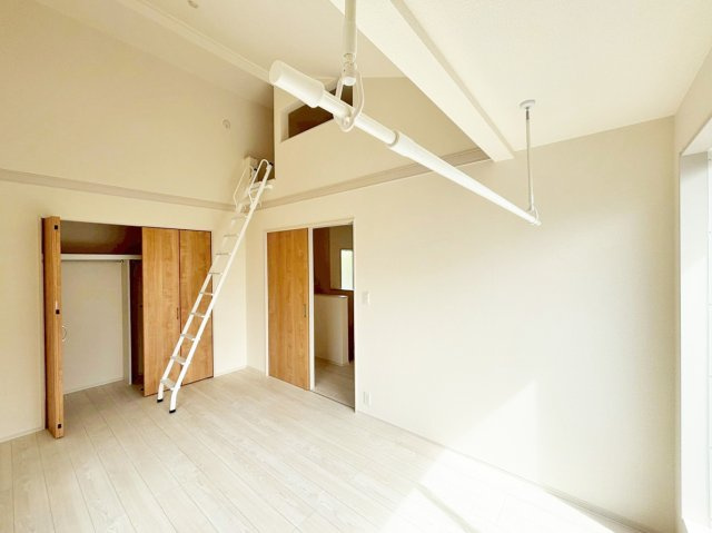 ブルーミングガーデン中山五月台1丁目新築一戸建て全2区画│3・4LDK+並列駐車2台可の洋室|2階主寝室想定に入ってすぐの内観写真です。勾配天井で開放感溢れる一室となっております。上部には室内物干し竿が設置されています。