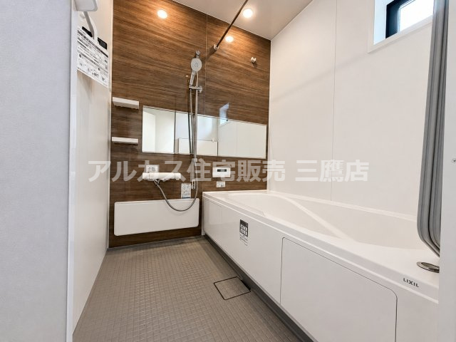 三鷹市井口５丁目 中央線 武蔵境駅 新築戸建の浴室| 木目調のアクセントパネルが落ち着いた雰囲気を醸し出すバスルームです。ワイドな横長鏡や小窓を備え、快適なバスタイムを楽しめます。