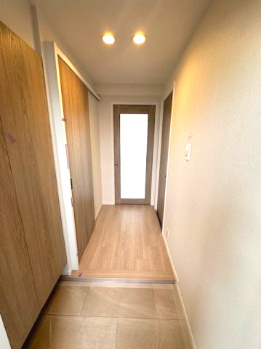 【玄関】 | パラツィーナセシリア豊中 | 玄関から各部屋へ繋がる廊下は、木のぬくもりと白を基調とした明るい空間です。※掲載中の写真は広角レンズで撮影のため、実際の見え方とは異なります。