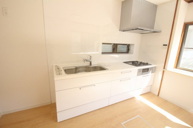 小山市中久喜1丁目のキッチン|1階キッチン6帖。新品のシステムキッチンに交換済み！3口コンロや広いシンクで、毎日の家事もスムーズです。清潔感のある白いデザインで気分も明るく。