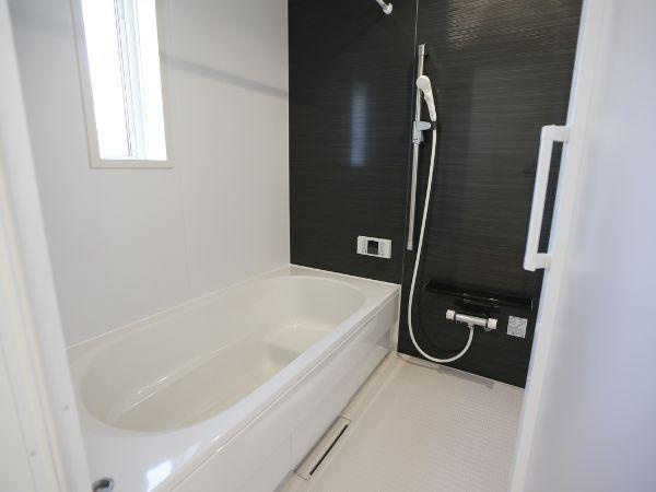 富士見が丘東第6-1号棟の浴室|明るいバスルームには清潔感があります。浴槽とシャワースペースがゆったりと設けられています。窓からの自然光が室内を照らします。壁面のダークカラーが空間を引き締めます。