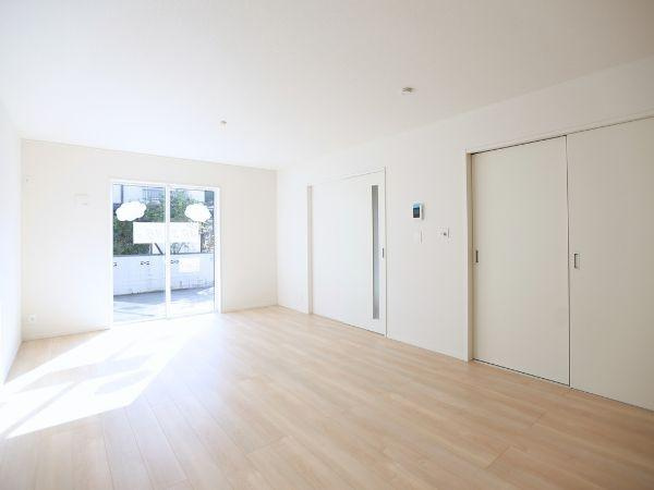 富士見が丘東第6-2号棟の居間・リビング|大きな窓から光が差し込む明るい空間です。床は淡い色合いですっきりとした印象です。収納扉も備わっており使い勝手に配慮されたリビングです。全体的にシンプルなデザインでまとめられています。