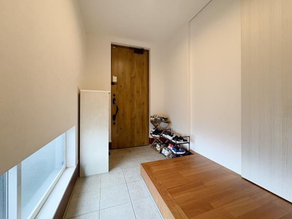 中戸次　中古の玄関|明るい印象の玄関スペースです。木目調の扉が落ち着いた雰囲気を演出します。大きな窓から自然光が差し込み開放的な空間となっています。靴収納も設置され使い勝手も意識されています。