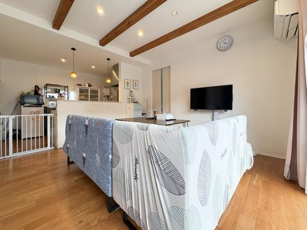 中戸次　中古の居間・リビング|リビングは木目調の床と梁がアクセントになっています。天井のスポットライトが明るさを演出し、キッチンと一体感のある空間が広がっています。