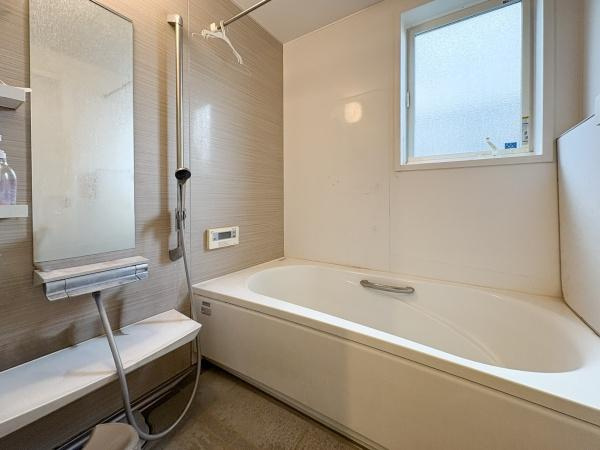 中戸次　中古の浴室|浴槽がゆったりとしたサイズ感でリラックスできる空間です。大きめの窓があり自然光が差し込みます。モダンな色合いの壁面と使いやすいシャワーが特徴です。清潔感のあるバスルームとなっています。