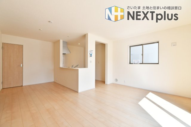 上尾市小敷谷第2全11棟　4号棟の居間・リビング|16.2帖の広々LDKは、キッチン上部の「下がり壁」が空間のアクセント。開放感を保ちつつ、注文住宅のようなメリハリある意匠性を実現しました。機能的な和室も隣接し、家族の時間を彩るこだわり設計です。