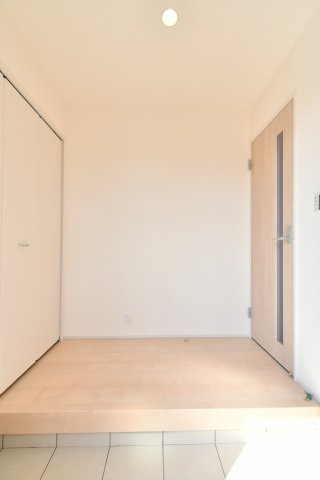 上尾市小敷谷第2全11棟　4号棟の玄関|白を基調とした内装と木目調のドアが調和する、開放感あふれる玄関ホール。無駄のない洗練されたデザインは、お好みのインテリアも映えます。ゆとりある上がり框が、ゲストを優雅に迎え入れる一邸。