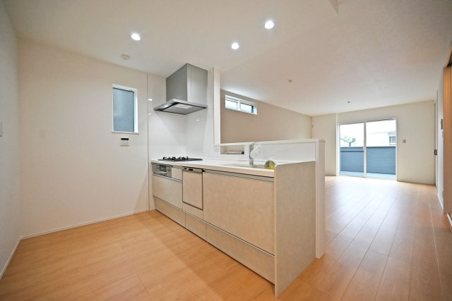 尼崎市大島1丁目新築戸建│南向き5LDK+駐車1台可のキッチン|2階LDKをキッチンユニット越しに撮影した内観写真です。対面式キッチンを採用しているため視界は広く、ご家族間やご来訪者とのコミュニケーションも一体的に取り易くなっております。