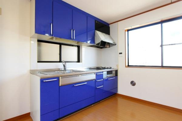 横浜市鶴見区潮田町１丁目の中古一戸建のキッチン|鮮やかなブルーのキッチンが空間にアクセントを加えています。窓から自然光がしっかり入り明るさを感じられます。豊富な収納スペースで使い勝手に配慮されています。ステンレス製の作業台が清潔感を演出しています。