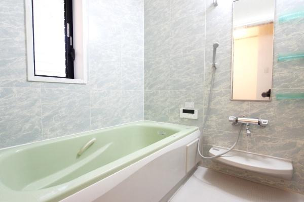 横浜市鶴見区潮田町１丁目の中古一戸建の浴室|清潔感のある壁面が特徴的なバスルームです。大きな鏡と便利な棚が設置されています。窓からは自然光が差し込み明るい印象です。広めの浴槽でリラックスできそうです。