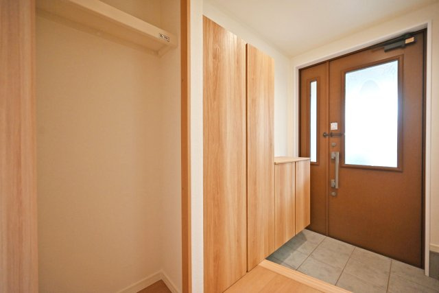 尼崎市食満5丁目中古戸建│4LDK+駐車1台可の玄関|1階玄関をホール側から撮影した内観写真です。シューズボックスを配置したオーソドックスな玄関です。シューズボックス横の収納庫内には枕棚とハンガーレールが配置されています。