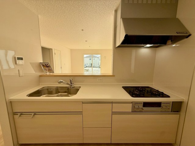 クレイドルガーデン南城市玉城前川 第3・５号棟のキッチン|レンジフード＆ガスコンロ３口＆浄水器付きキッチン／リビングの眺め