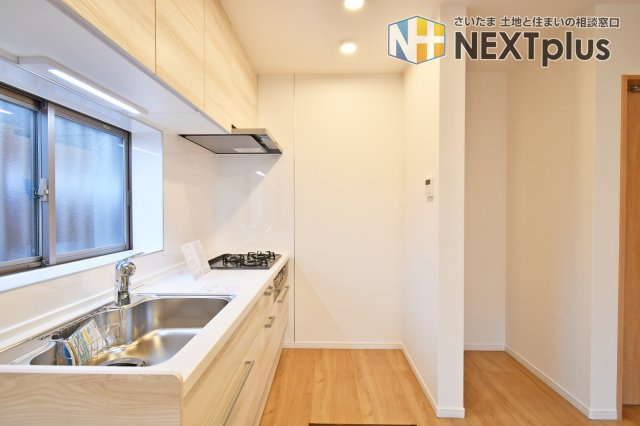 久喜市本町二丁目戸建のキッチン|木目基調の吊戸棚付きシステムキッチンです。上にも下にもたくさん収納出来ますので、別途で食器棚がなくてもたくさん収納する事ができます！ライトもありますので、お料理中の手元もしっかり照らしてくれます。