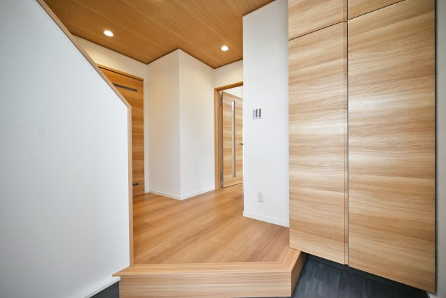 宝塚市今里町中古戸建｜4LDK+駐車1台可の玄関|1階玄関に入ってすぐの内観写真です。 上部まで収納があるシューズボックス付き。天井に木目のアクセントクロスやダウンライトを配置するなど、一工夫加えられています。