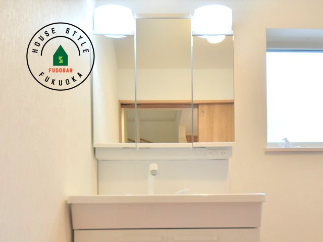 福津市若木台6丁目第2-1棟（1号棟）の内観：施工例|毎日使うものだから清潔な空間を保ちたい水回り。洗面にはそんな願いを解消させてくれる収納アイデアが満載です。三面鏡の裏側にはキャビネットが現れ小物から背の高い物まで収納できます。