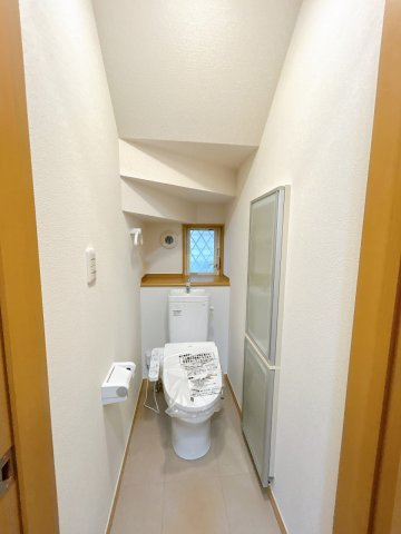 小山市犬塚7丁目のトイレ|階段下を活用したトイレは圧迫感がなく、窓付きで換気もしやすい造りです。温水洗浄便座で毎日を快適にお使いいただけます。