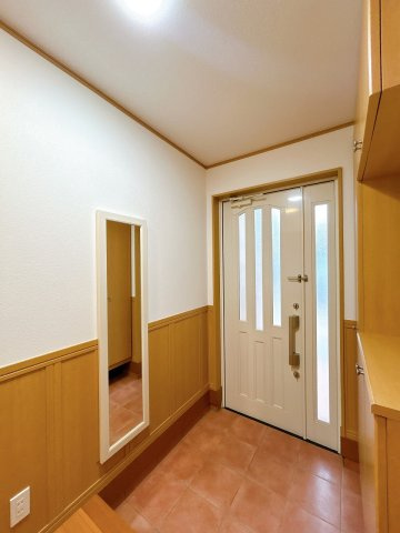 小山市犬塚7丁目の玄関|タイル張りの玄関は明るく開放的です。姿見付きでお出かけ前の身だしなみチェックにも便利。収納もありスッキリ保てます。