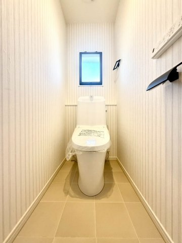 ガーデン南山手のトイレ|採光窓付きで明るいトイレ。温水洗浄便座と収納棚を備え、清潔で快適な空間に仕上がっています。