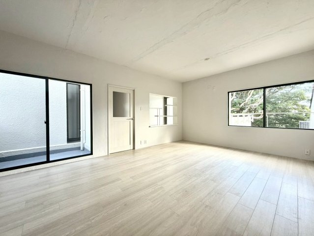 ガーデン南山手の居間・リビング|大きな窓から光が差し込むリビングは開放感たっぷり。白基調の壁と木目フロアが柔らかく調和した上質な空間です。