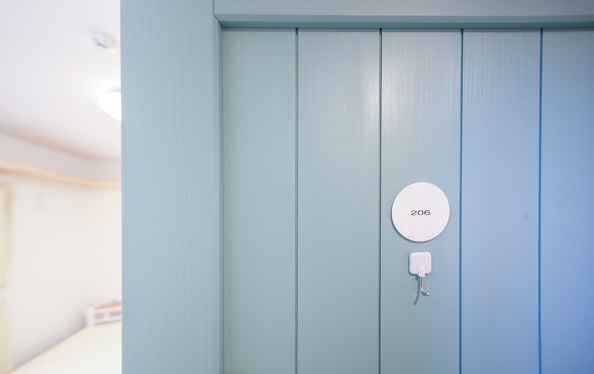 ぬこハウス小岩の洋室|個室２０６号室：個室に専用洗面台、キャットウォーク、マットレス、エアコン、カーテン、室内外洗濯物干しを完備。個室扉：グリーン、アクセントクロス：イエロー。
