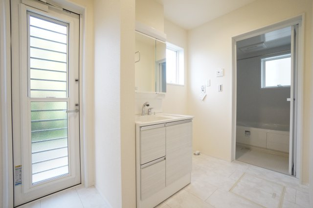 リーブルガーデン武豊町冨貴市場　1号棟の独立洗面台|勝手口がある洗面室は明るく風通しも良く快適♪シャワー付き洗面化粧台は、伸ばせる水栓で洗面台でのシャンプーや洗い物に便利な仕様。