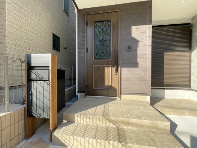 北区志茂3丁目 全3棟 1号棟の玄関|明るいタイルと木目ドアが調和した、温もりあふれるエントランスです(1号棟)