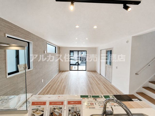 【内覧動画公開中！】三鷹市牟礼５丁目 井の頭線 三鷹台駅 新築戸建の居間・リビング|対面キッチンからリビングを見渡せる間取り。木目調の床とアクセントウォールが温かみのある空間を演出します。
