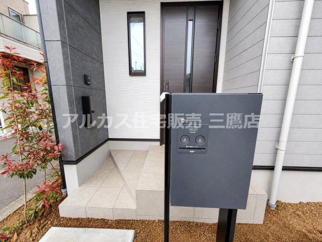 【内覧動画公開中！】三鷹市牟礼５丁目 井の頭線 三鷹台駅 新築戸建の玄関|宅配ボックスを備えた玄関まわり。タイル仕上げのアプローチと植栽が、端正な印象を演出します。
